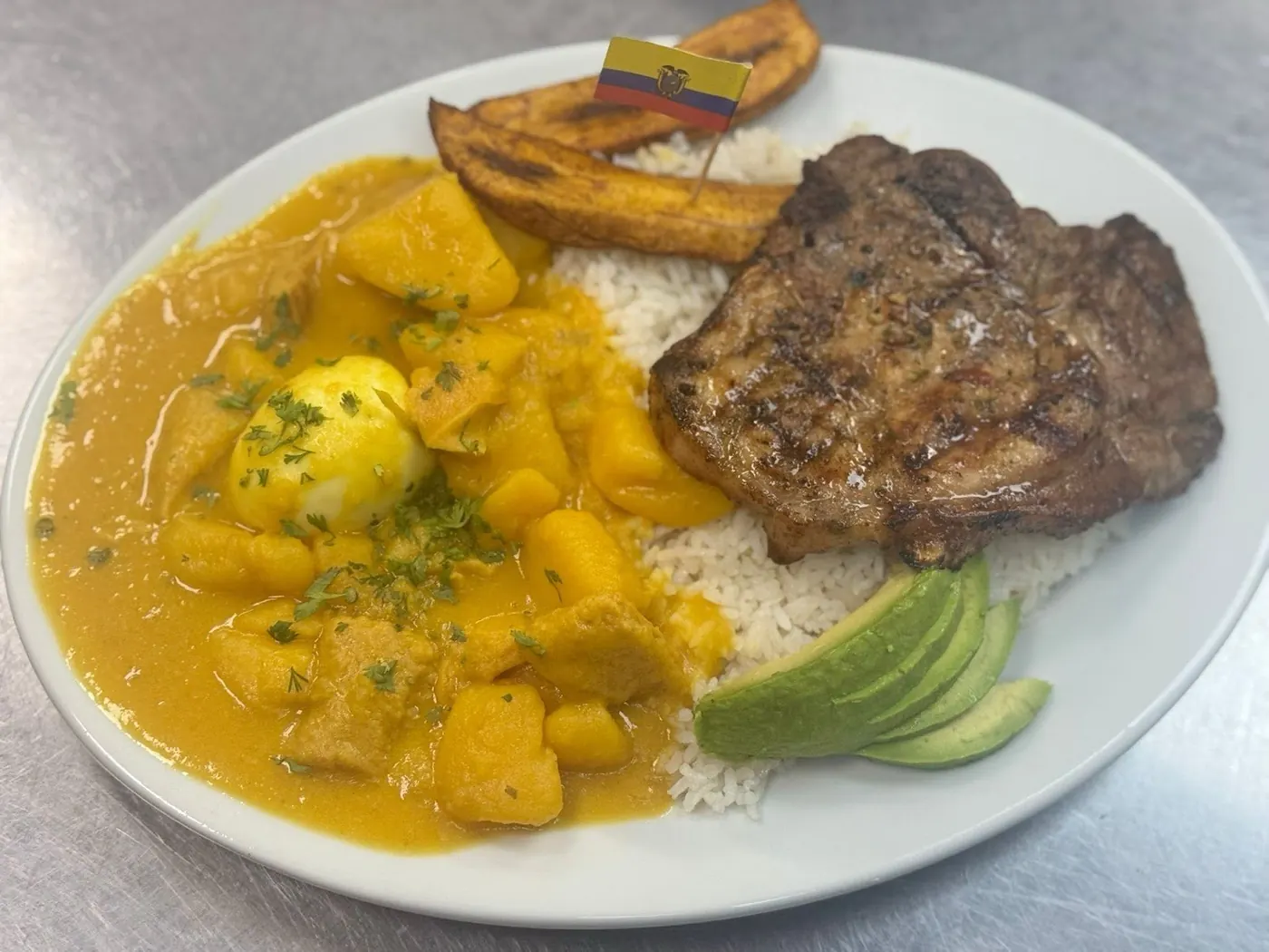Chuleta a la parrilla sobre guatita, con arroz, maduro y aguacate